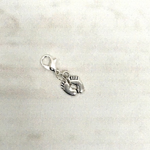 May include: Silver charm with a pair of baby footprints.