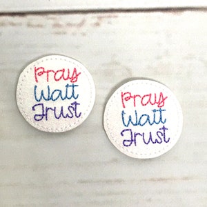 May include: Two white round felt patches with the words "Pray Wait Trust" embroidered in pink, blue, and white.
