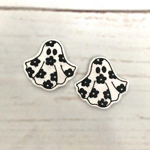 May include: Two white ghost-shaped fabric patches with black floral patterns and black eyes.