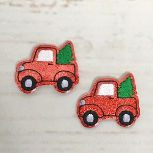 May include: Two red glitter truck ornaments with green glitter Christmas trees in the back.