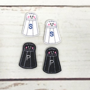May include: Four embroidered salt and pepper shakers with happy faces. Two are white with the letter "S" and two are black with the letter "P".