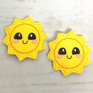 May include: Two yellow felt sun appliques with embroidered smiling faces, black eyes, and pink cheeks.