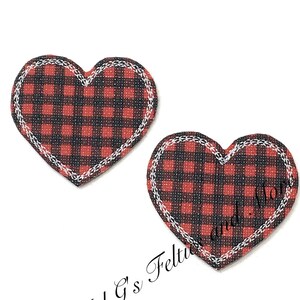 以下が含まれることがあります： 白いステッチが縁取られた、赤と黒の格子柄のハート型のフェルトパッチが2つです。
