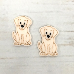 May include: Two white felt dog appliques with brown embroidered details. The dogs are sitting with their paws together and have black embroidered eyes.
