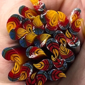 Op de afbeelding: Set van drie keramische mokken met een gespikkelde, crèmekleurige glazuur. Elke mok heeft een handgeschilderd bloemmotief in blauw, groen en geel. De mokken hebben een eenvoudige, moderne vorm met een comfortabele handgreep.