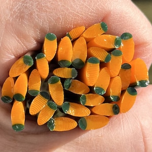 May include: A pile of orange and green glass rods, with a textured surface, are held in a hand. The rods are approximately 1/2 inch in diameter.