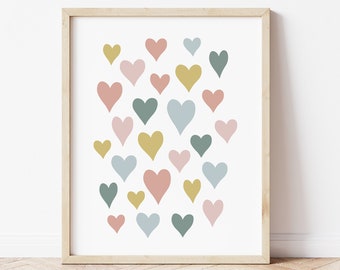 Puede incluir: Una impresión artística enmarcada con un patrón de corazones en rosa, azul, verde y amarillo. Los corazones están sobre un fondo blanco, y el marco es de madera clara. La obra de arte es adecuada para la decoración del hogar.