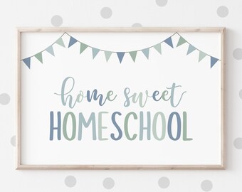 Pode incluir: Uma impressão emoldurada com as palavras "home sweet homeschool" em escrita azul e verde. Uma faixa de triângulos azuis e verdes pende sobre o texto. A impressão está em uma moldura de madeira clara.