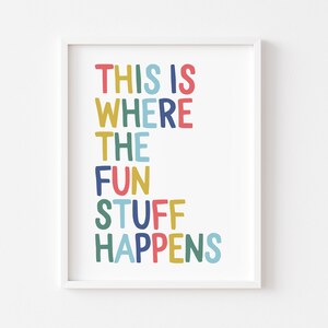 May include: A framed print with the words "THIS IS WHERE THE FUN STUFF HAPPENS" in colorful, playful lettering. The text is in red, blue, yellow, green, and teal, set against a white background. The print is in a white frame.