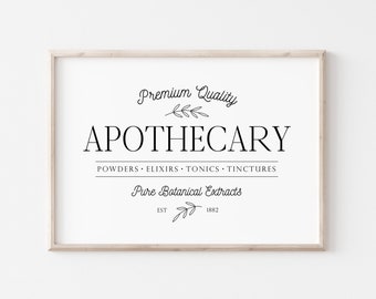 May include: A framed print with the word "APOTHECARY" in a serif font. The print includes the text "Premium Quality," "Powders, Elixirs, Tonics, Tinctures," and "Pure Botanical Extracts." The frame is a light wood color.