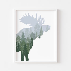 May include: Framed art print featuring a moose silhouette filled with a forest scene. The moose is in shades of gray and the forest is in shades of green. The artwork is displayed in a white frame.