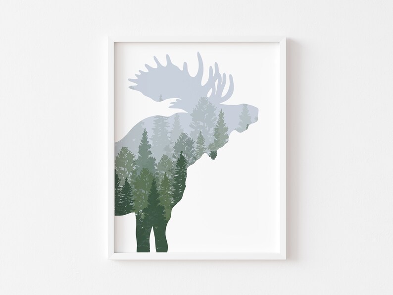 May include: Framed art print featuring a moose silhouette filled with a forest scene. The moose is in shades of gray and the forest is in shades of green. The artwork is displayed in a white frame.