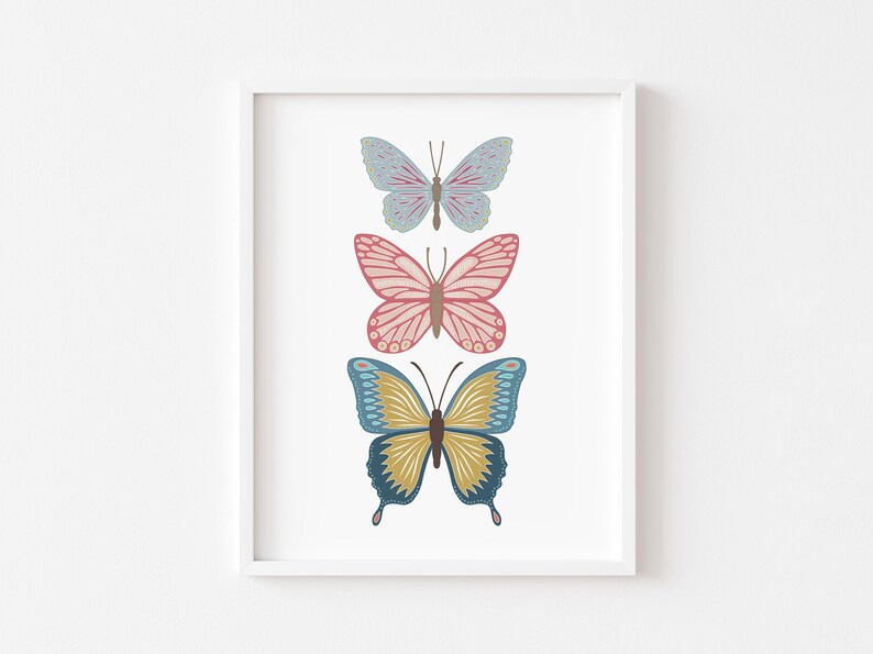 May include: A framed print featuring three colorful butterfly illustrations. The butterflies are arranged vertically, with a light blue butterfly at the top, a pink butterfly in the middle, and a blue and yellow butterfly at the bottom.