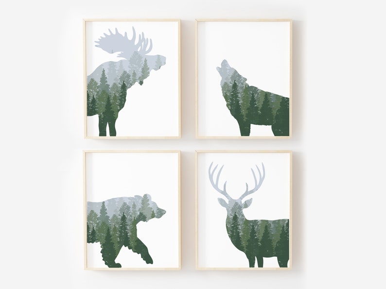 May include: Four framed art prints featuring forest animal silhouettes filled with a forest scene. The animals include a moose, a wolf, a bear, and a deer. The art prints have a white background and a light wood frame.