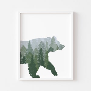 May include: Framed art print featuring a silhouette of a bear filled with a forest scene. The artwork uses shades of green and gray to depict the trees and mountains, creating a nature-themed aesthetic. The print is set against a white background.