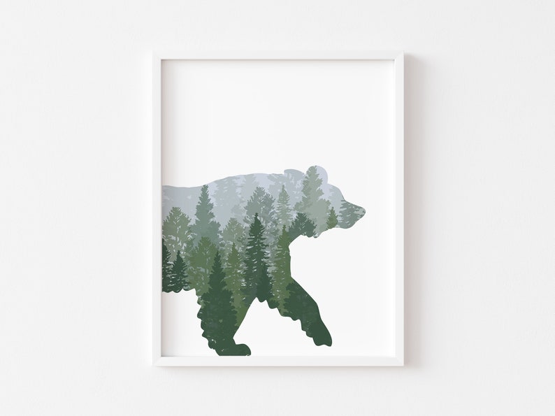 May include: Framed art print featuring a silhouette of a bear filled with a forest scene. The artwork uses shades of green and gray to depict the trees and mountains, creating a nature-themed aesthetic. The print is set against a white background.