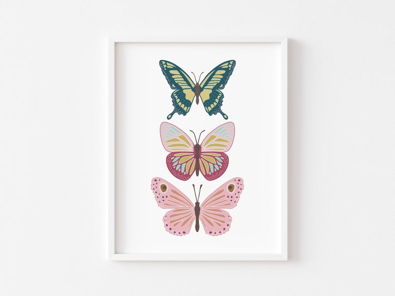 May include: A framed print featuring three colorful butterfly illustrations. The top butterfly is teal and yellow, the middle one is pink and yellow, and the bottom one is pink with brown spots. The butterflies are set against a white background.