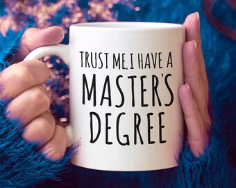 May include: White ceramic coffee mug with black text that reads "Trust me, I have a Master's Degree".