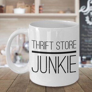 May include: White ceramic coffee mug with black text that reads "Thrift Store Junkie".