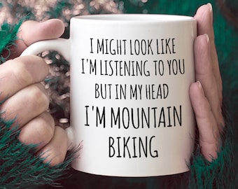 May include: White ceramic coffee mug with black text that reads "I might look like I'm listening to you but in my head I'm mountain biking".