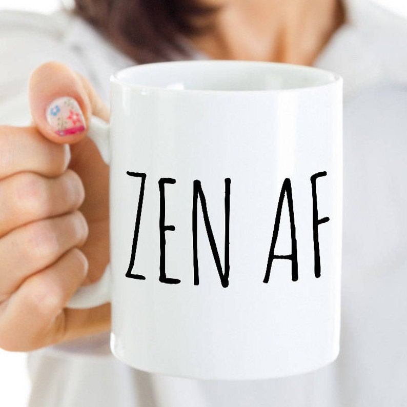 May include: White ceramic coffee mug with black text that reads "ZEN AF".