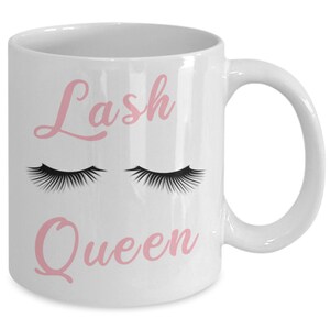 May include: White ceramic coffee mug with the text "Lash Queen" in pink script. Two black eyelashes are above the text.