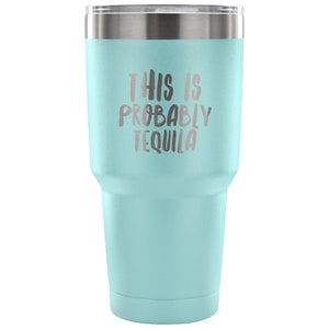 May include: A light blue stainless steel tumbler with a white lid. The tumbler has the text "This is probably tequila" printed on the side.