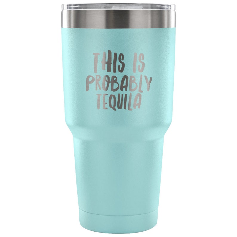 May include: A light blue stainless steel tumbler with a white lid. The tumbler has the text "This is probably tequila" printed on the side.