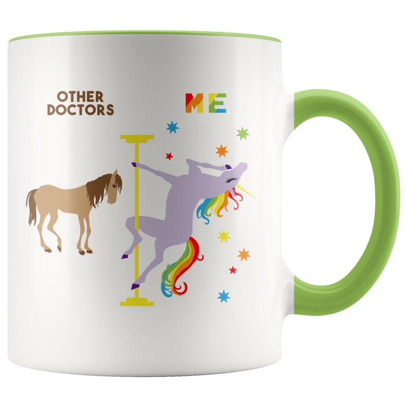 May include: White ceramic coffee mug with a green rim and handle. The mug features a graphic of a unicorn doing a pole dance with the text "OTHER DOCTORS" on the left and "ME" on the right.