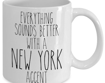 Può includere: Tazza in ceramica bianca con manico curvo. La tazza presenta un testo nero che recita: "EVERYTHING SOUNDS BETTER WITH A NEW YORK ACCENT."
