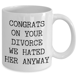 May include: White ceramic coffee mug with black text that reads "Congrats on your divorce we hated her anyway".