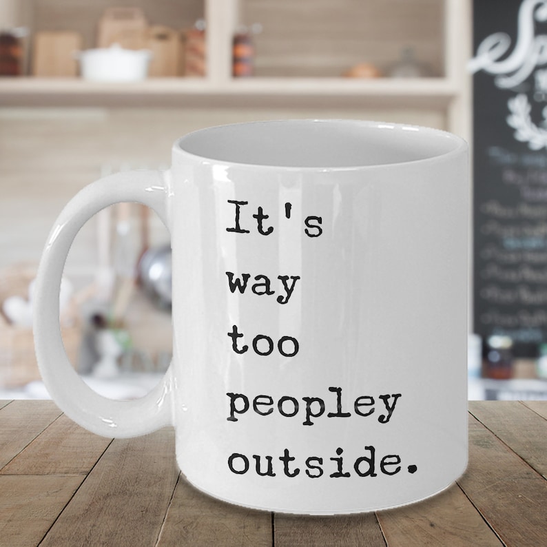 May include: White ceramic coffee mug with black text that reads "It's way too peopley outside."