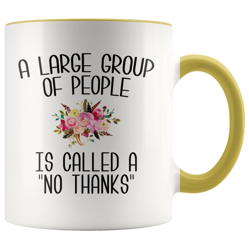 May include: White ceramic mug with a yellow rim and handle. The mug features a floral design and the text "A large group of people is called a "no thanks""