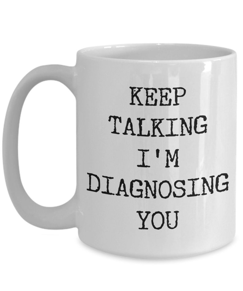 May include: White ceramic coffee mug with black text that reads "Keep Talking I'm Diagnosing You".