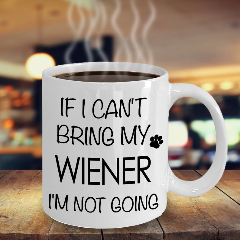 May include: White ceramic coffee mug with black text that reads "If I can't bring my wiener I'm not going". A paw print is next to the word "wiener".