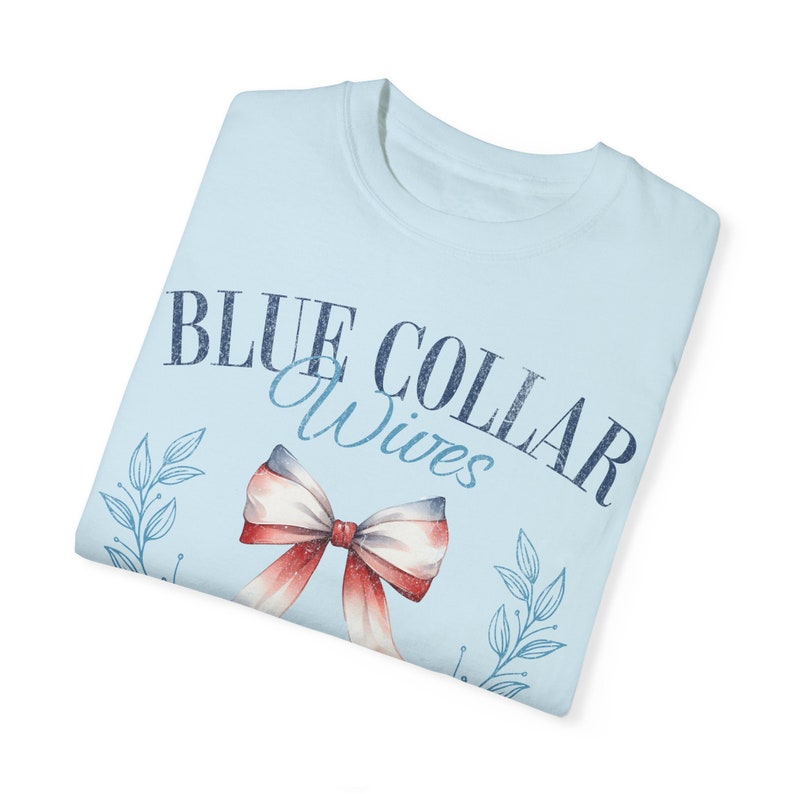 May include: Light blue t-shirt with a blue and white bow and the text "BLUE COLLAR Wives" printed on the front.