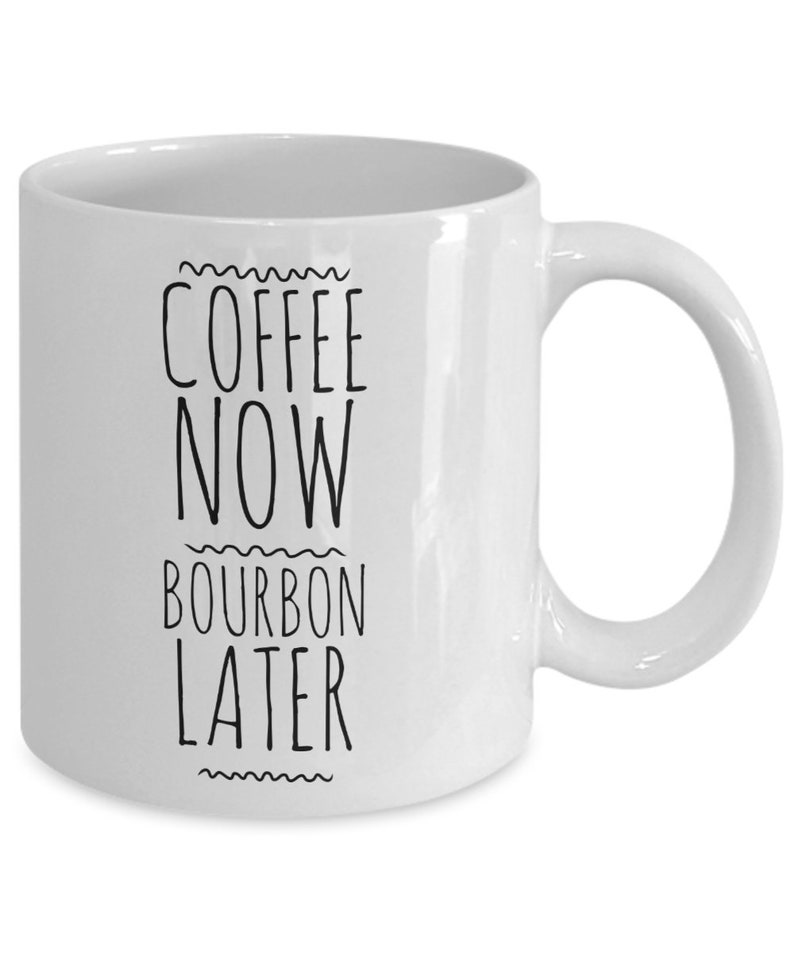K&ouml;nnte beinhalten: Wei&szlig;e Keramik-Kaffeetasse mit schwarzem Text, der "Coffee Now Bourbon Later" lautet.