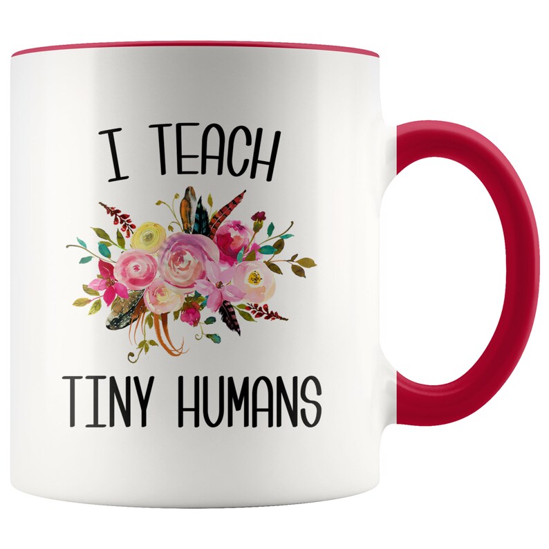 Peut inclure: Une tasse &agrave; caf&eacute; en c&eacute;ramique blanche avec un bord et une poign&eacute;e rouges. La tasse pr&eacute;sente un motif floral et le texte "J'enseigne de minuscules humains".