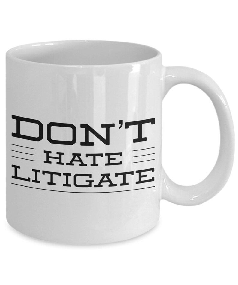 May include: White ceramic coffee mug with black text that reads "DON'T HATE LITIGATE".