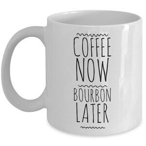 K&ouml;nnte beinhalten: Wei&szlig;e Keramik-Kaffeetasse mit schwarzem Text, der "Coffee Now Bourbon Later" lautet.