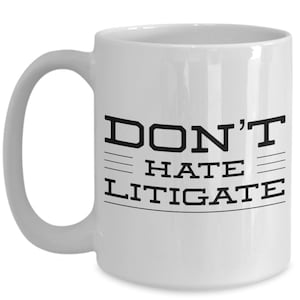 May include: White ceramic coffee mug with black text that reads "DON'T HATE LITIGATE".