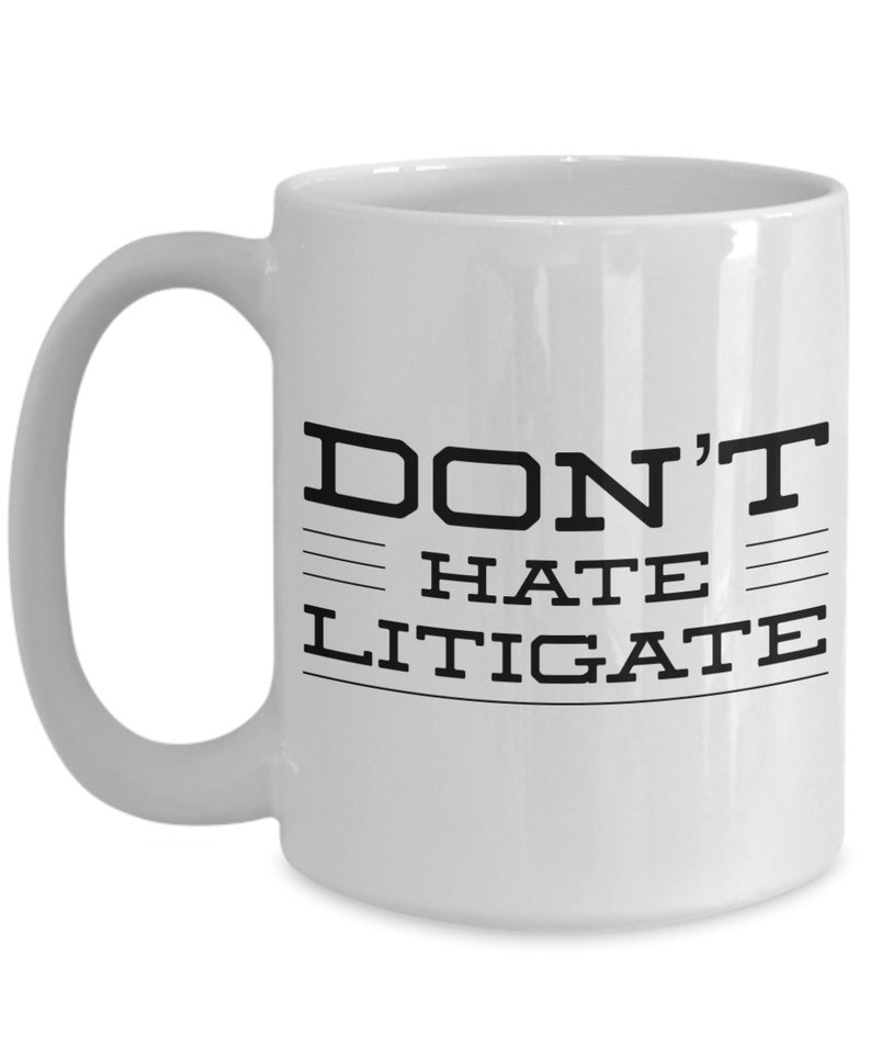 May include: White ceramic coffee mug with black text that reads "DON'T HATE LITIGATE".