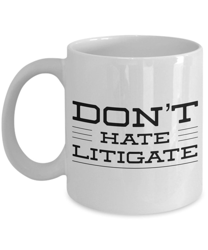 May include: White ceramic coffee mug with black text that reads "DON'T HATE LITIGATE".