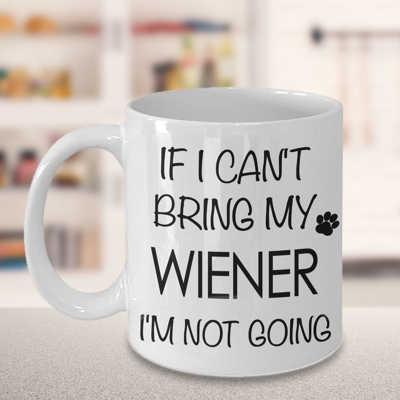 May include: White ceramic coffee mug with black text that reads "If I can't bring my wiener I'm not going" with a paw print icon.