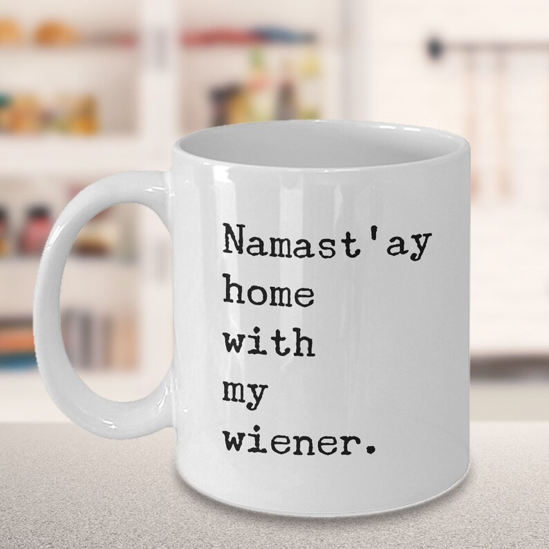 May include: White ceramic coffee mug with black text that reads "Namaste'ay home with my wiener."