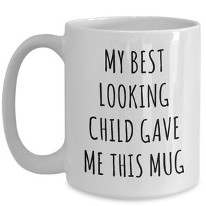 May include: White ceramic coffee mug with black text that reads "My best looking child gave me this mug".