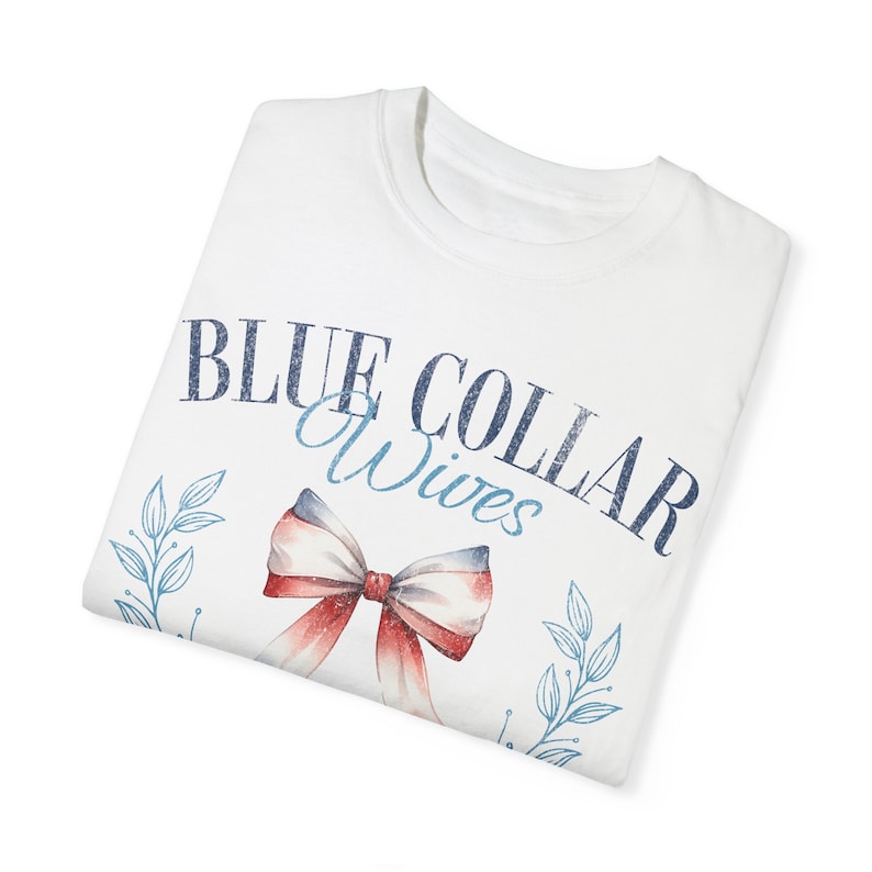 May include: White t-shirt with a blue and red design that says "BLUE COLLAR Wives" with a red and blue bow and blue leaves.
