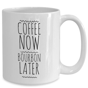 K&ouml;nnte beinhalten: Wei&szlig;e Keramik-Kaffeetasse mit schwarzem Text, der "Coffee Now Bourbon Later" lautet.