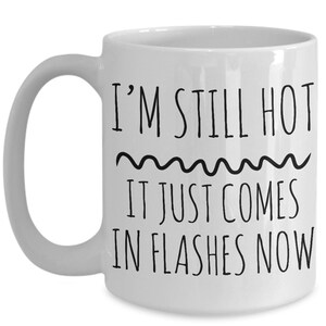 Puede incluir: Taza de caf&eacute; de cer&aacute;mica blanca con texto negro que dice "I'm still hot it just comes in flashes now".