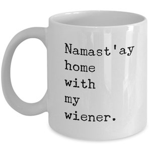 May include: White ceramic coffee mug with a black text design that reads "Namaste'ay home with my wiener."